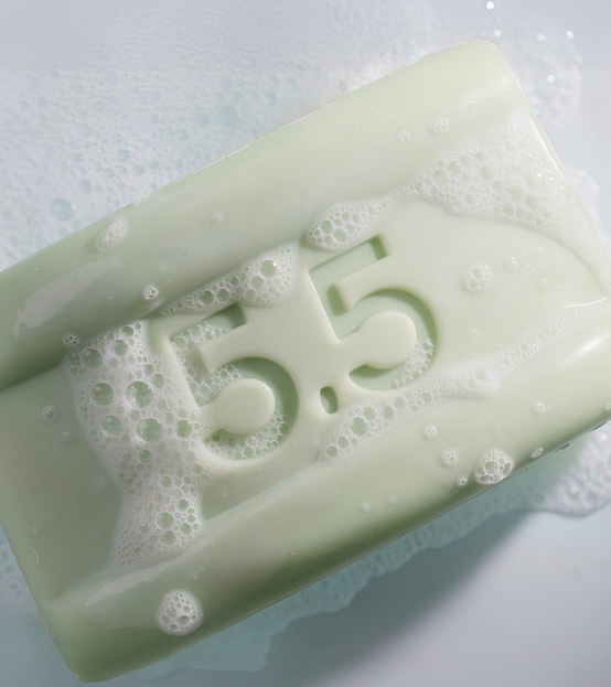 Ein grüner Seifenriegel mit der Aufschrift 5.5, der in Schaum getaucht ist.