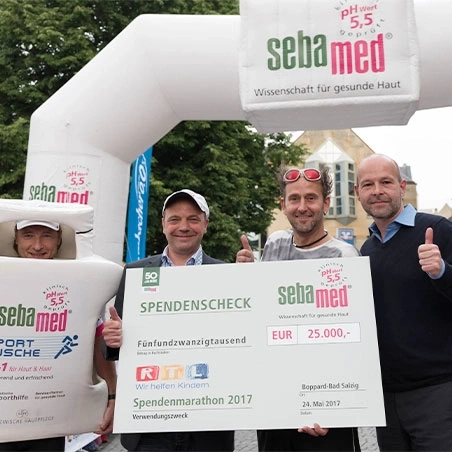 Sebamed-Spendenmarathon: Scheckübergabe mit Spendenscheck und Personen