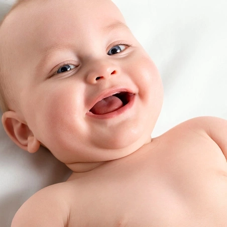 Glückliches Baby, das in die Kamera lächelt, mit offenem Mund und Zunge.