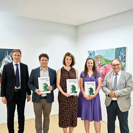 Fünf Personen stehen nebeneinander und halten Broschüren.