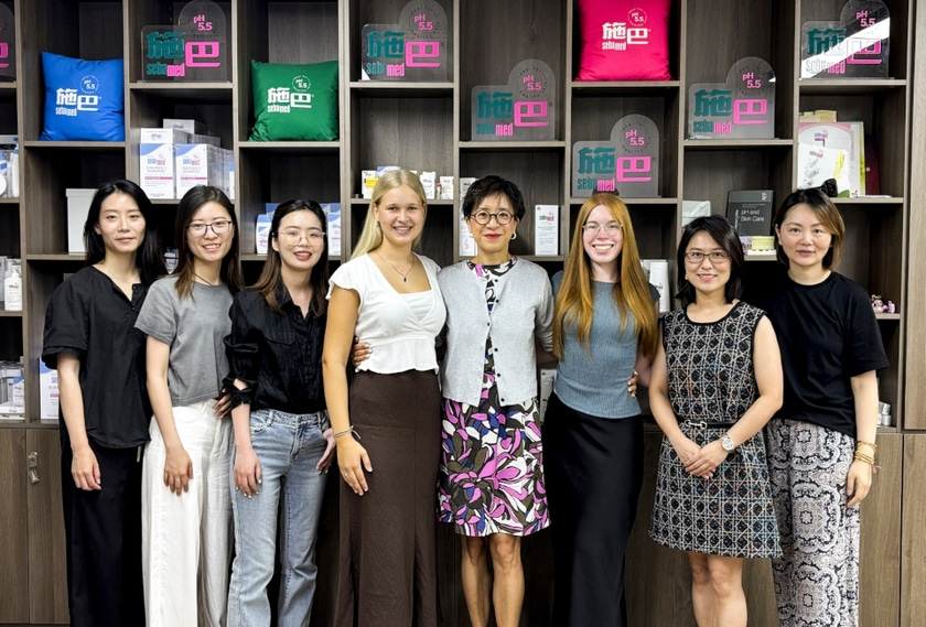 Eine Gruppe von Mitarbeiterinnen von sebamed vor einem Werberegal mit Produkten