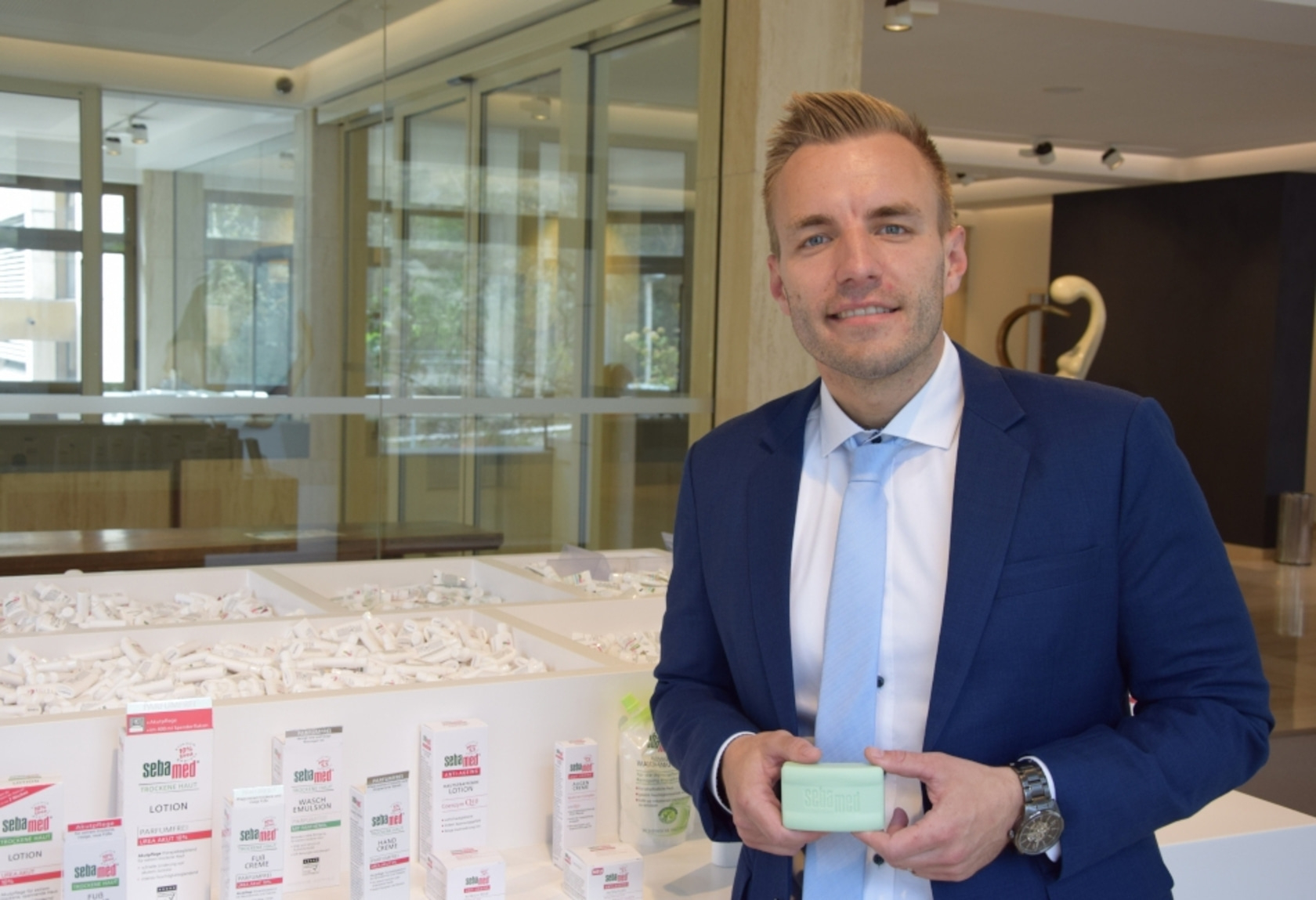 Ein Mann in einem Anzug hält ein Stück Seife vor einer Produktpräsentation.