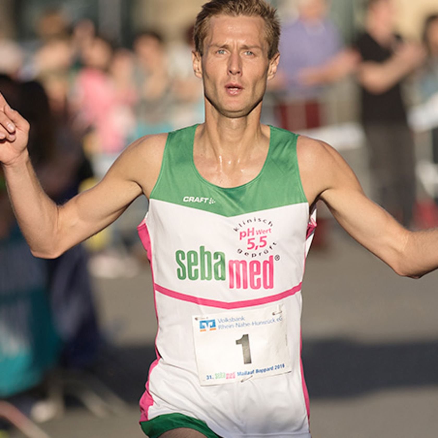 Ein Läufer mit der Nummer eins, der ein grünes und weißes Trikot trägt, rennt.