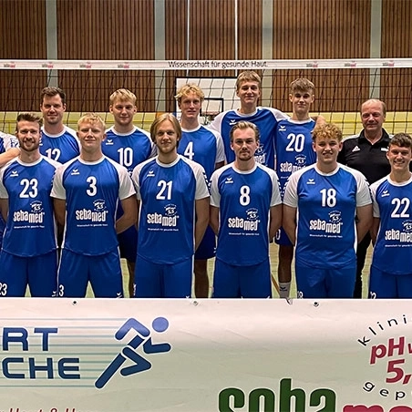 Volleyballteam in blauen Trikots mit Werbung, stehend für ein Foto.