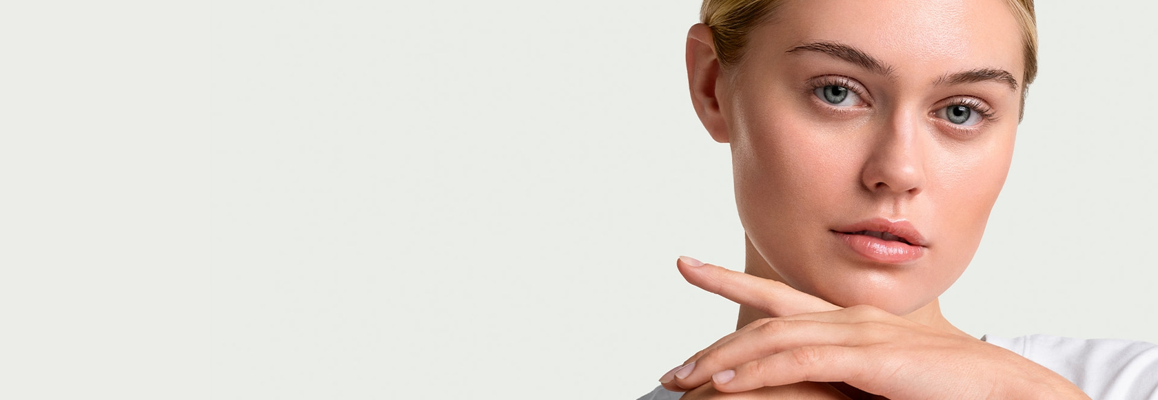 Nahaufnahme einer Frau mit blonden Haaren, die ihre Hand an ihr Kinn legt.
