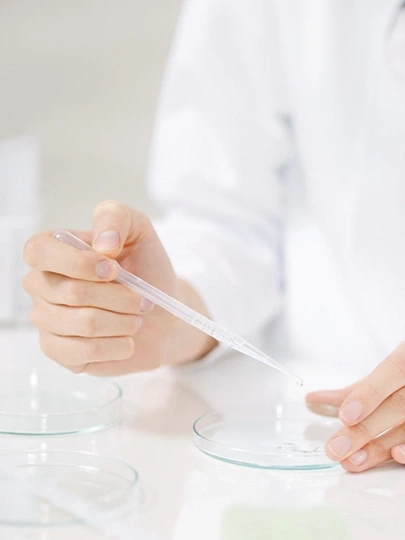 Eine Person, die mit einer Pipette in einem Labor arbeitet, um Flüssigkeit zu dosieren.
