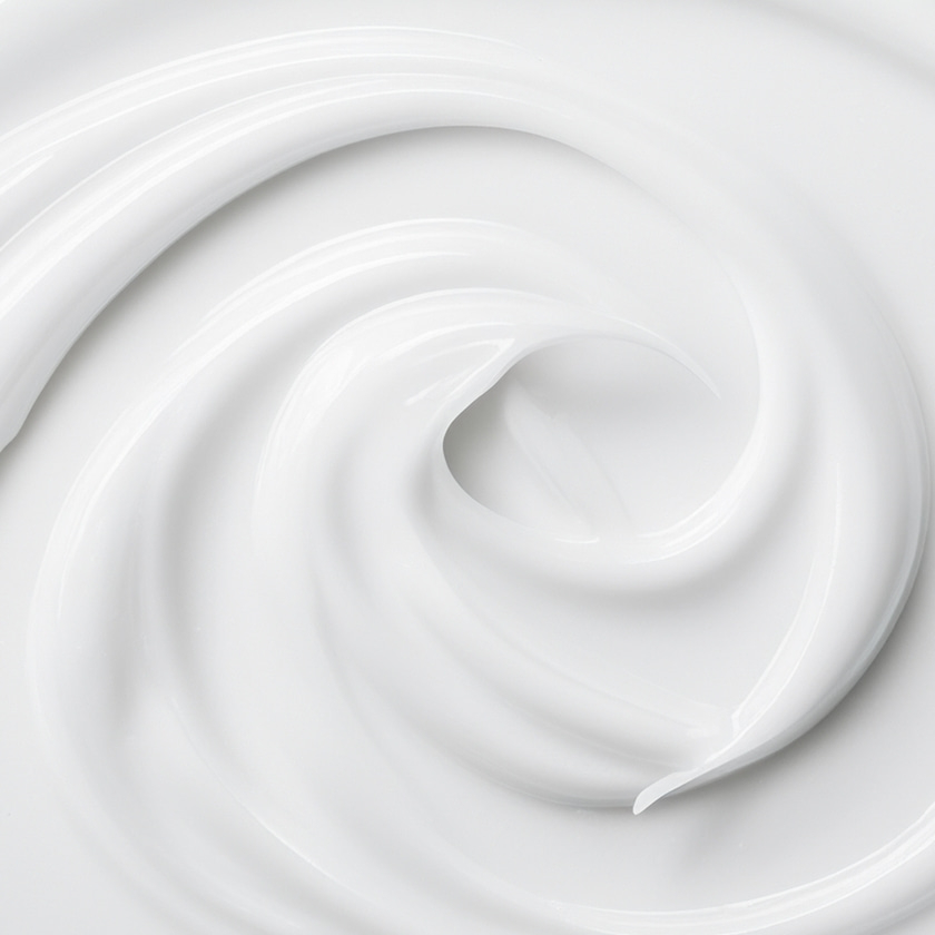 Nahaufnahme von weißer Creme, die sich in einer spiralförmigen Bewegung dreht und glänzt.