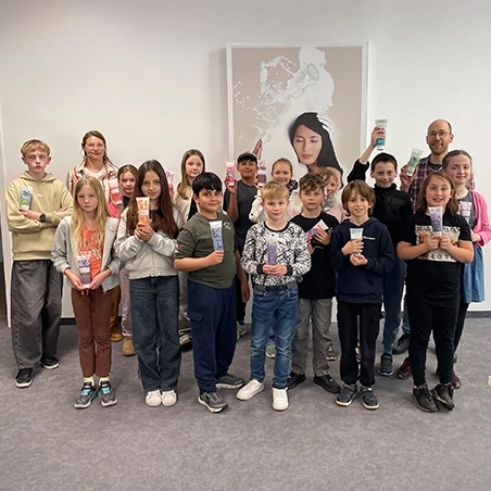 Eine Gruppe von Kindern und Erwachsenen hält Tuben mit Kosmetikprodukten.