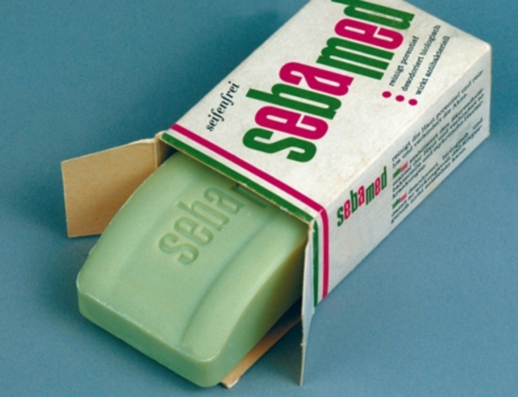 Sebamed Seife in der Verpackung, grün, geöffnet, auf blauem Hintergrund