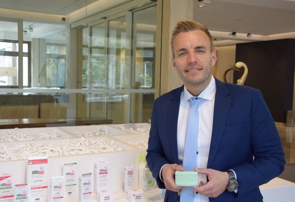 Ein Mann in einem Anzug hält ein Stück Seife vor einer Produktpräsentation.