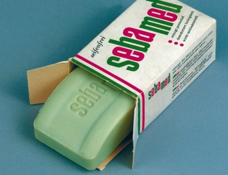 Sebamed Seife in der Verpackung, grün, geöffnet, auf blauem Hintergrund